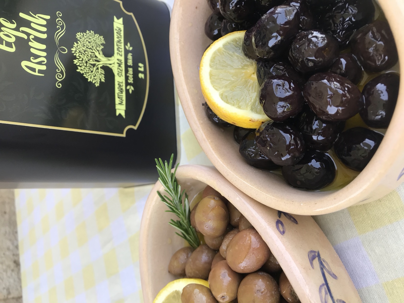 İki kasede siyah ve yeşil sofralık zeytin, arkada 2 litrelik zeytinyağı tenekesi